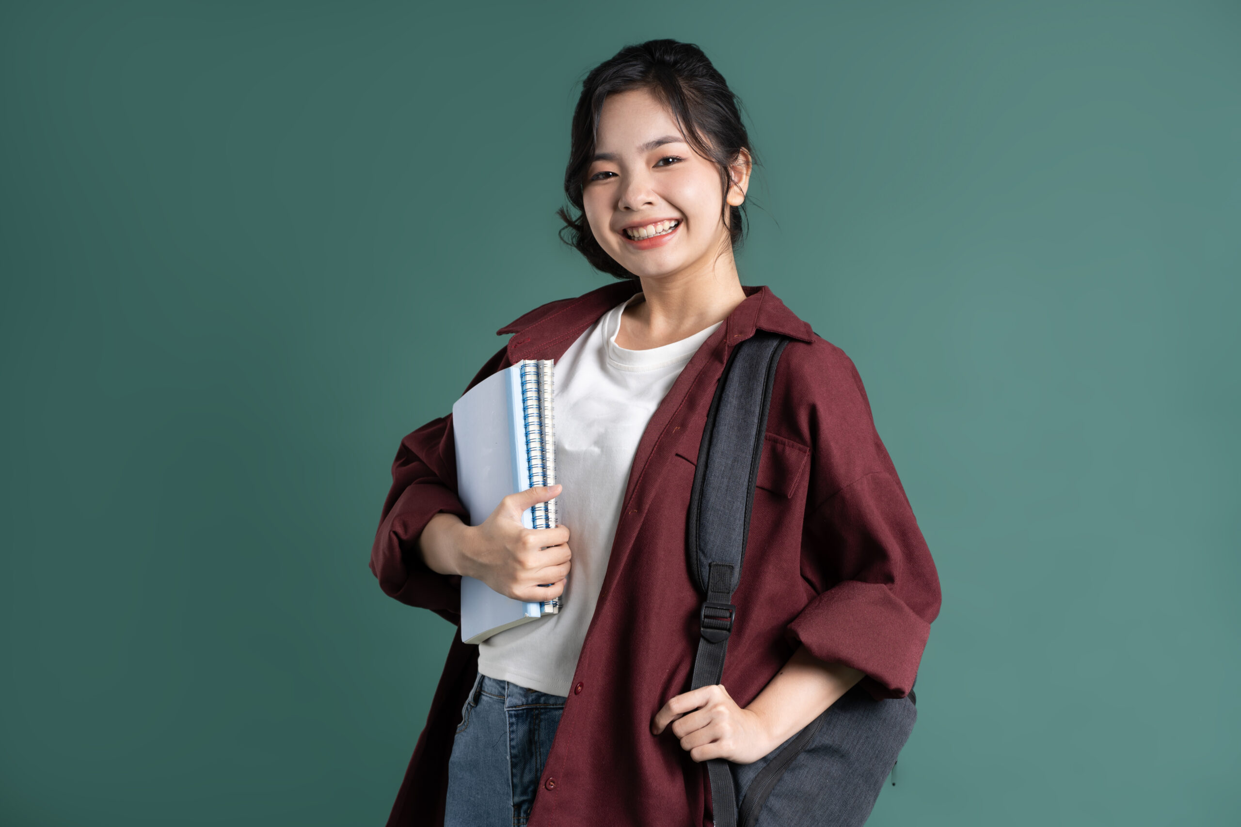 Portrait of a beautiful Asian student on a green background